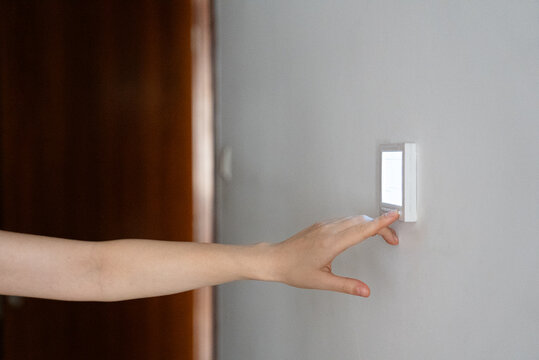 Hand turning on light switch on wall electricity and home interior concept