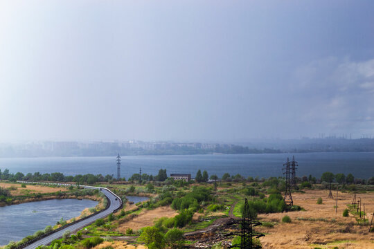 Rainstorm over lake and industrial cityscape