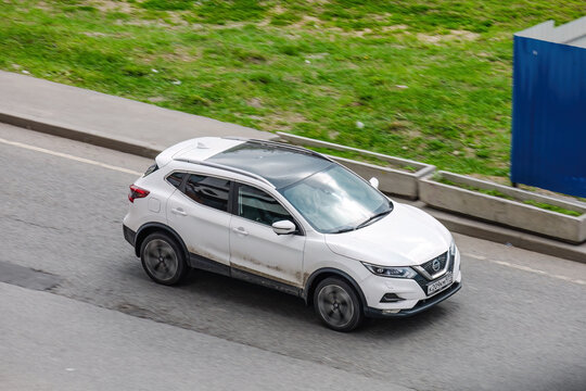 Nissan Qashqai Second generation J11 rides on urban road. Overspeed in city concept. White SUV in motion, above front side view