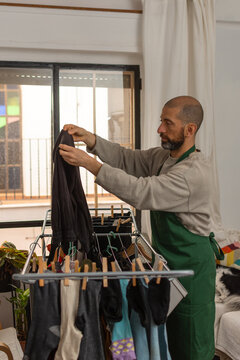 Hispanic man removing dry pants from rack preparing to fold