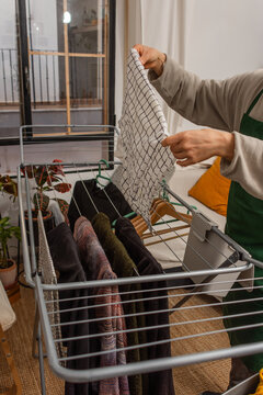Close up of hands hanging kitchen towel on drying rack at home