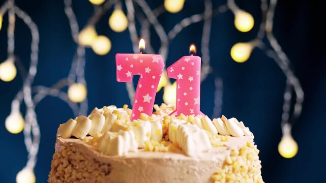Birthday cake with a pink number 71 candle on background captured in slow motion and close-up view shows a meaningful celebration moment as the candle flame is blown out.