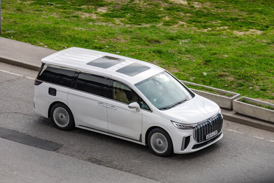 Voyah Dream plug-in hybrid minivan rides on road. Above front side view of white MPV in motion