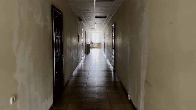 Slow walking through the long dark empty hallway with closed doors