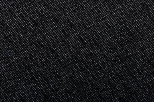 Macro Close-up of Black Ripstop Fabric Texture with Grid Pattern,High-detail macro shot of a durable black ripstop nylon material, showcasing the reinforced square grid weave and technical fiber.