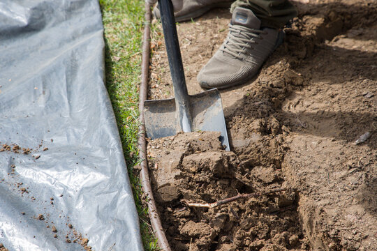 Worker digging a hole in the ground with a shovel, close-up