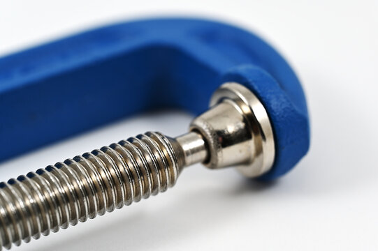 a threaded steel screw and blue C-clamp mechanism