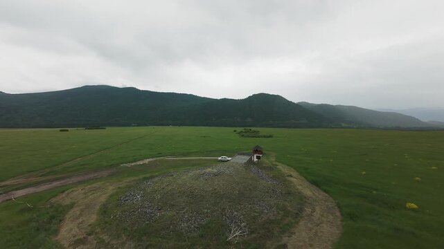 FPV drone flight over the modern circular museum building and ancient Scythian burial mound. Located in the Berel Valley of the Kings, Altai Mountains, East Kazakhstan