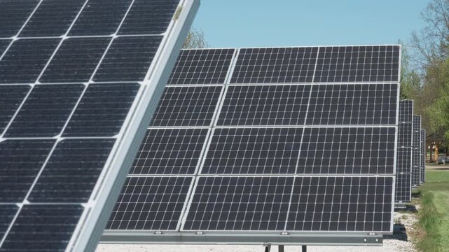 Rows of bifacial photovoltaic solar panels on ground mount racking system. Industrial renewable energy farm using white gravel for albedo effect to maximize power generation yield outdoors.