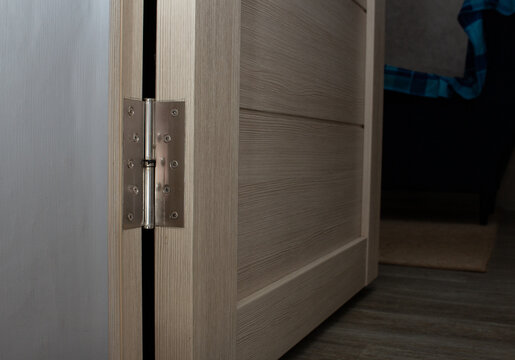 Door hinge mounted on wooden cabinet door during furniture installation
