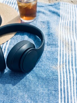 Wireless headphones on towel by swimming pool during summer vacation