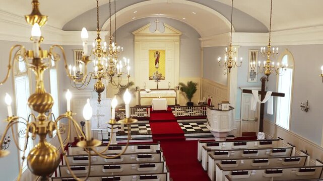 On the balcony of a Catholic cathedral church with red carpet and white pews with several crosses before mass.