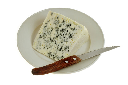Morceau de R&eacute;gal&iacute;s Bleu au lait de Brebis dans une assiette avec un couteau en gros plan isol&eacute; sur fond blanc