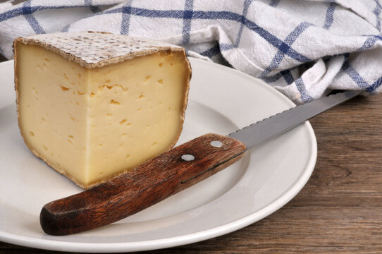 Morceau de tomme de Yenne dans une assiette avec un couteau en gros plan