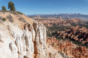Bryce Canyon white limestone cliffs overlooking orange hoodoo formations and vast desert valleys beneath a clear blue sky in Utah’s dramatic canyon landscape. © Jacqueline