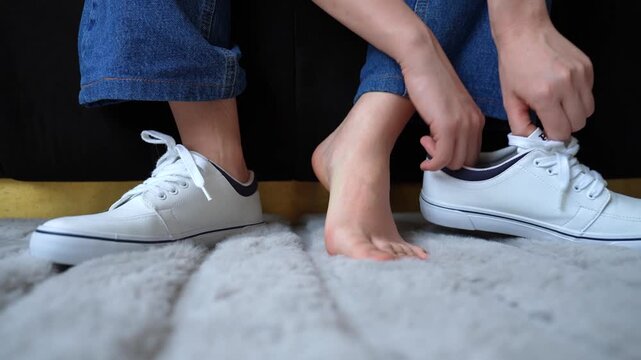 Woman removes shoe, scratches itchy foot and puts on white loafer. Concept of discomfort, irritation, tired feet and everyday hygiene. 