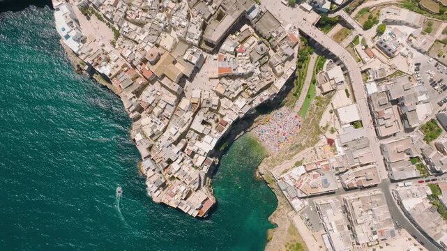 Aerial drone view of Polignano a Mare town in Puglia, Italy. Scenic coastal architecture, historic buildings, and beach by the Mediterranean sea during summer vacation.
