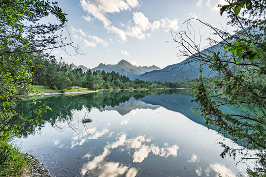 Beautiful View of Lake Baggersee near Weissenbach am Lech with Mountain Peaks Reflection, Scenic Alpine Landscape with Clear Water and Pine Forest under Clouds in Tyrol Austria in Summer