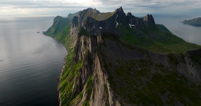 Wide panoramic drone view of entire dramatic mountain ridge of Segla, surrounded by ocean on island of Senja, Norway. Aerial