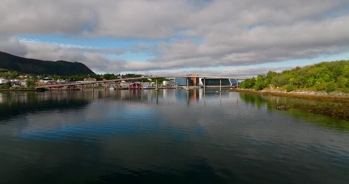 Cinematic drone dolly forward over the calm waters of Stokmarknes, Norway, revealing the iconic bridge and modern architecture. Perfect for travel and Nordic lifestyle projects