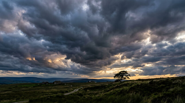 Dramatic landscape with dark stormy clouds at sunset over rolling hills and a lonely tree