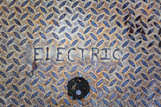 Electric manhole cover close up, a metal surface.