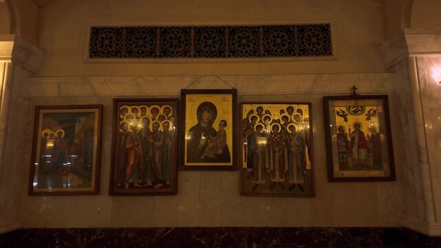 Detailed close-up of several vibrant Orthodox icons displayed on a marble wall within the Holy Trinity Cathedral in Tbilisi, highlighting the rich artistic and religious heritage.
