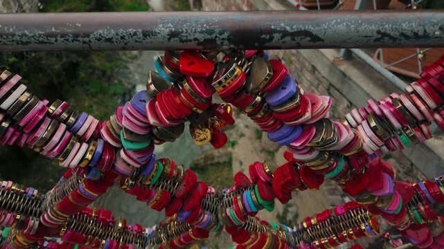 Love locks of various colors and shapes adorn a metal bridge railing above a flowing stream in Tbilisi. Many heart shaped locks symbolize everlasting love and commitment from visitors to the city.