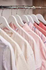 Clothing rail of neatly arranged pastel pink ombre t-shirts on white hangers, minimalist wardrobe display for boutique or closet photography © Rychko Yevhen