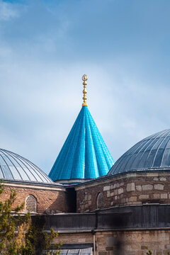 A majestic vertical view of the fluted turquoise dome at the Mevlana Museum in Konya, Turkey. The shot captures the golden finial and stone architecture against blue sky. Islamic cultural heritage.