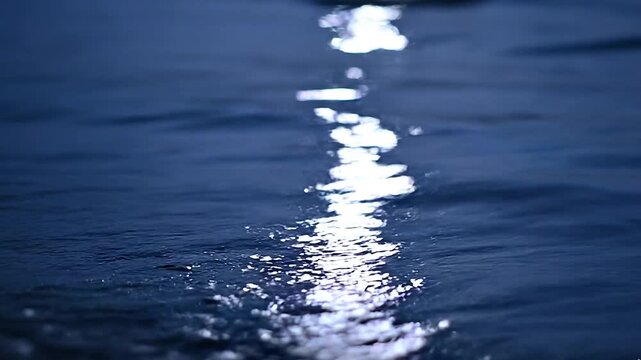 Calm ocean surface at night with moonlight reflection