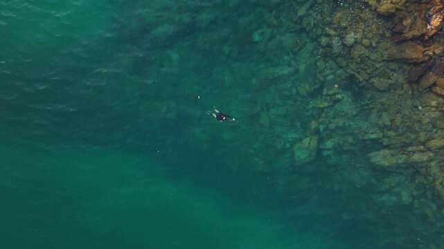 Aerial view of the spearfisherman hunting in the sea. Aerial top down view of the hunter in the water