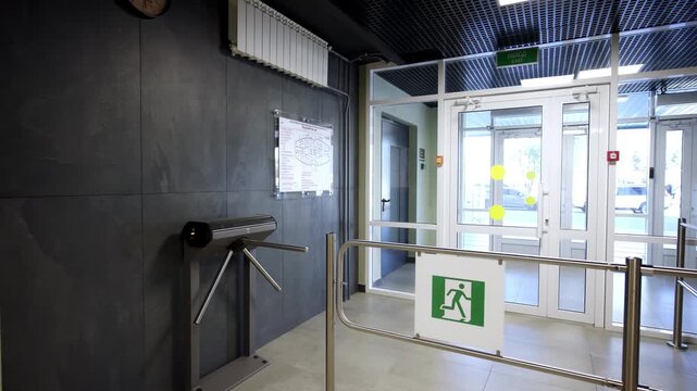 Security entrance features metallic tripod turnstile and glass doors. Dark textured stone walls create sophisticated business look