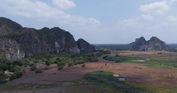 backward aerial view of rugged limestone karsts and patchy agricultural 