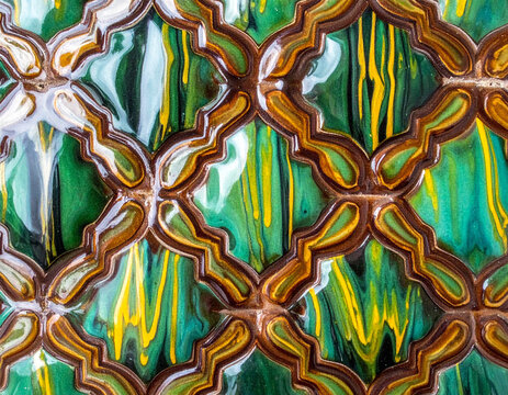 Close-up of a Kosiv ceramic tile showing the unique green and yellow lead glaze drips and the brown etched outlines.