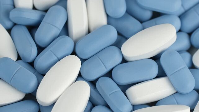 Mixed blue and white pills, rotation. Pharmaceutical Industry concept