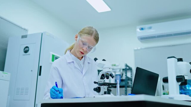 Female scientist in laboratory for medical research and product testing. Concept of medical innovation using microscope in modern lab for biotechnology development.