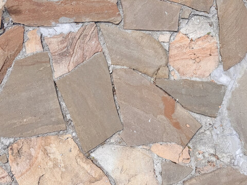 Irregular stone paving with natural beige and terracotta flagstone pieces creating rustic pattern
