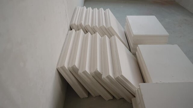 Minimalist view of white gypsum boards stacked for renovation project. Neutral color palette and soft light create industrial background for building or repair concepts
