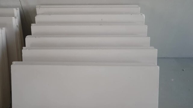 Minimalist abstract background featuring stacked white architectural moldings. Repetitive geometric steps create pattern texture. Neutral gray white color palette. Concept for construction design