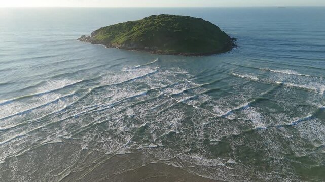 Aerial view of the island in the sea with waves interfere next to it