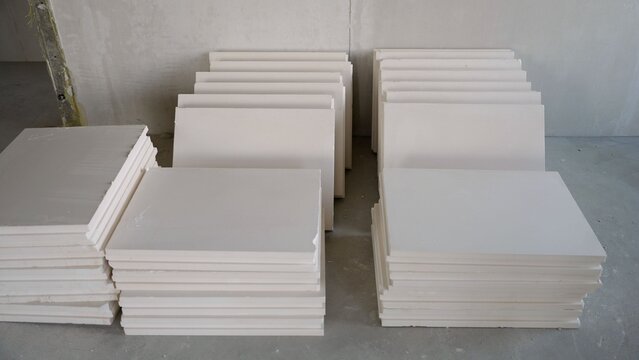 Stacks of white plasterboard panels on concrete floor during renovation