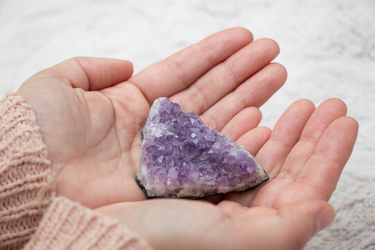  Manos de mujer sosteniendo una piedra amatista natural para meditaci&oacute;n, ambiente espiritual