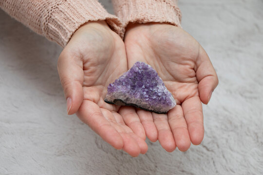 manos de mujer mostrando una piedra amatista, primer plano, luz natural, ambiente relajante y espiritual