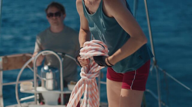 Woman sailor works with rope on a sailing boat. Couple sailing in the tropical calm sea during nice sunny day
