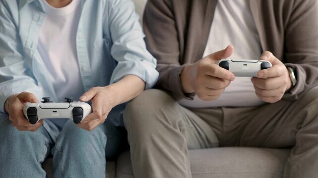 Two people sitting on a couch playing video games with controllers