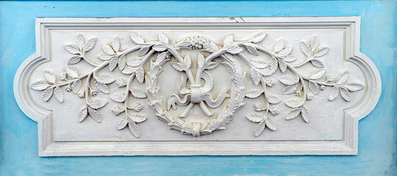 Neoclassical plaster relief with floral garlands and republican architectural decoration detail. 