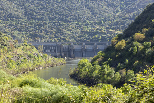 View of the Douro River dam surrounded by steep hills and lush green vegetation in Portugal.