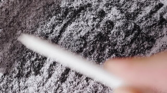 close up of chalk pencil drawing on textured black paper. slow motion footage. Background video can be used as overlay. doodling hatching