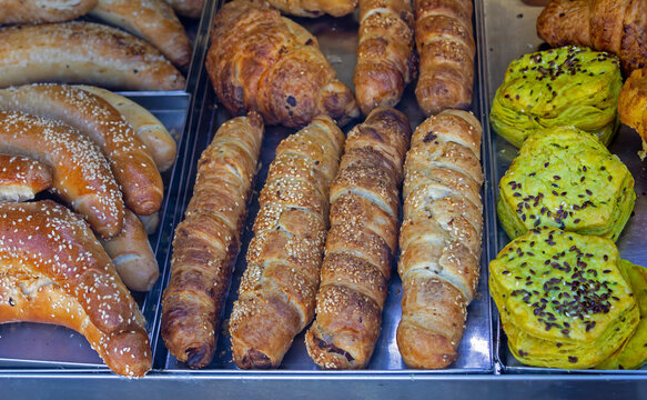 Sausage rolls buns and other pastry inside bakery interior shelf